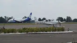 Взлёт самолёта Boeing 737-800 авиакомпании Belavia в аэропорту Брест, стоит легкомоторный Cirrus SR22